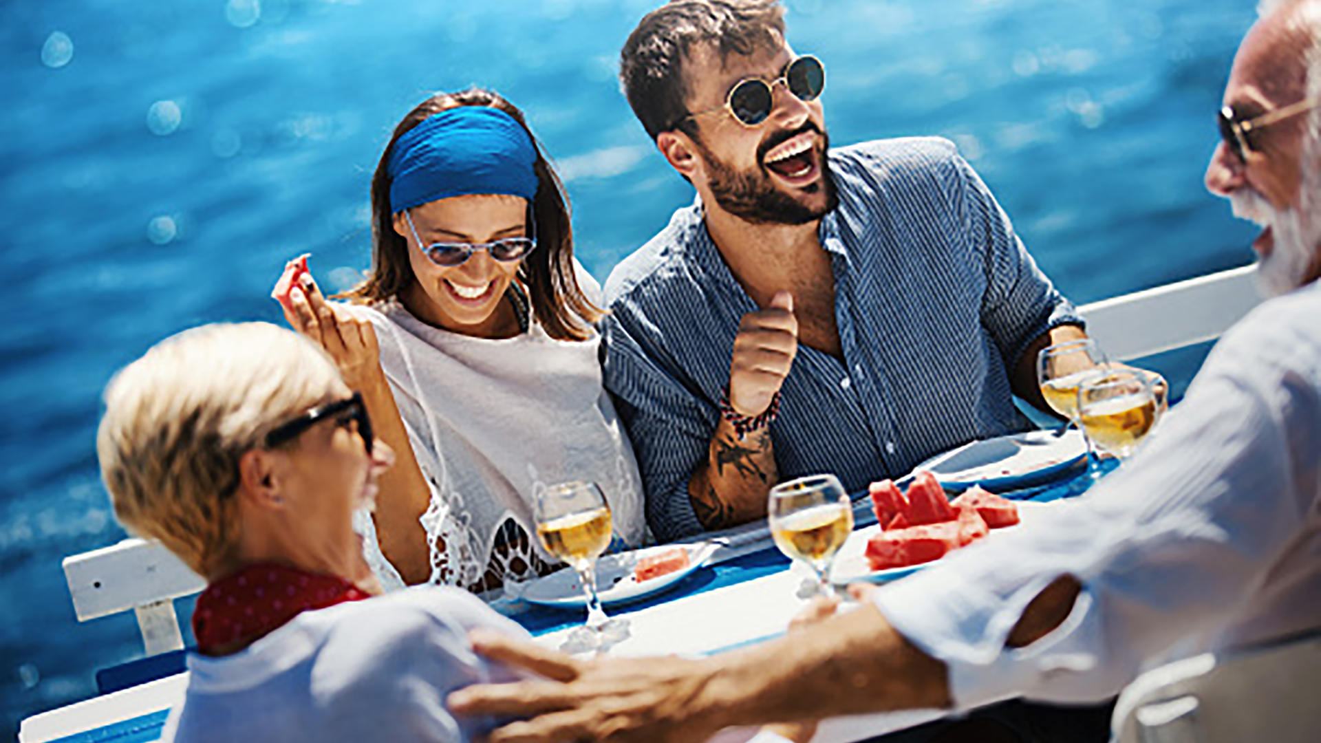 Closeup side view of a senior couple having lunch with their son and his fiancee while sailing during their summer vacation.